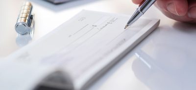 a person writing on a piece of paper with a pen.