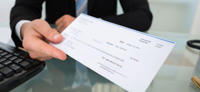 a man in a suit is holding a cheque.