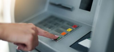 a person pressing a button on an atm machine.