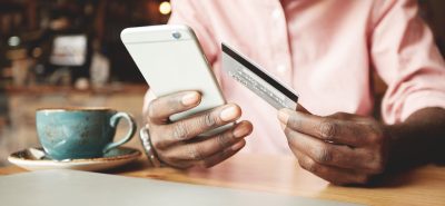 a man sitting at a table holding a smart phone.